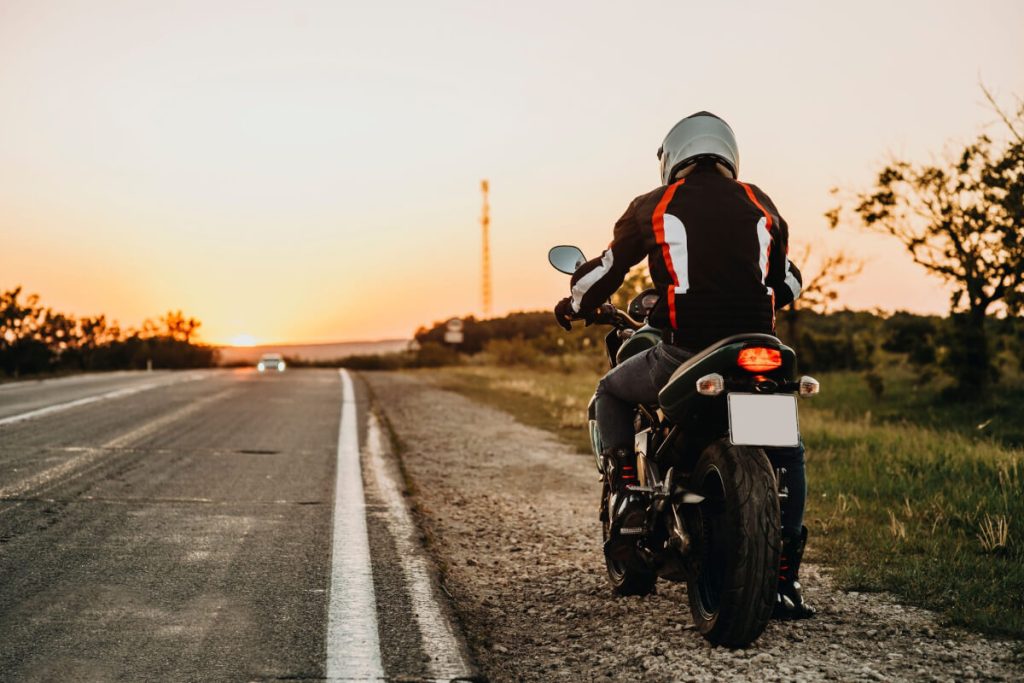 夕暮れを見つつバイクを走らせようとするライダー